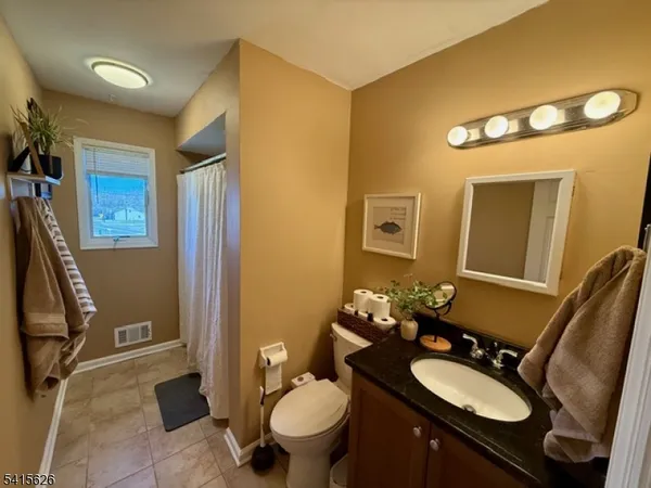 a bathroom with a granite countertop sink mirror vanity and toilet