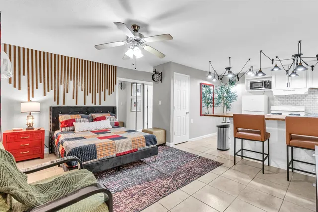 a bedroom with a bed a chandelier and mirror