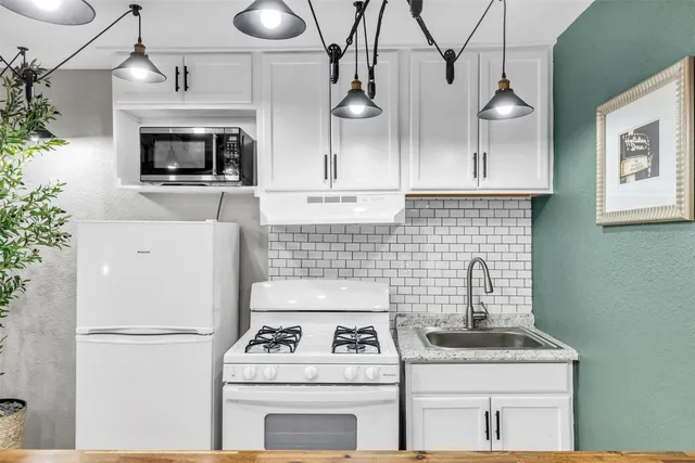 a kitchen with stainless steel appliances granite countertop a stove a microwave and a refrigerator