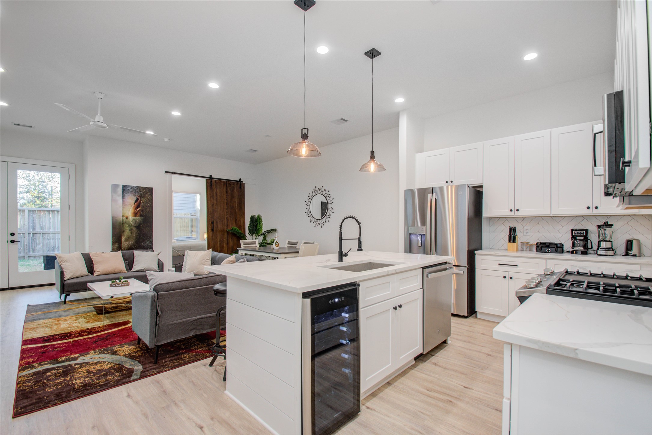 a open kitchen with stainless steel appliances granite countertop a sink dishwasher a refrigerator and white cabinets with wooden floor