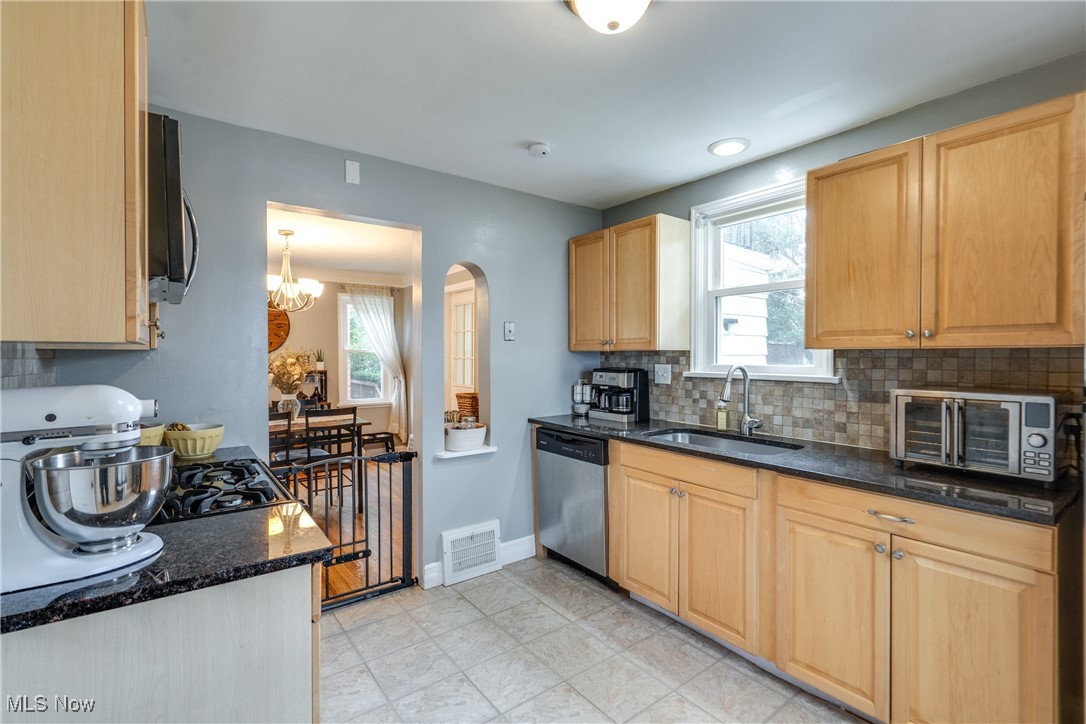 1375 Gordon Road Lyndhurst, OH 44124 - Photo 15 of 34 Kitchen with stainless steel appliances, light brown cabinets, a chandelier, backsplash, and arched walkways