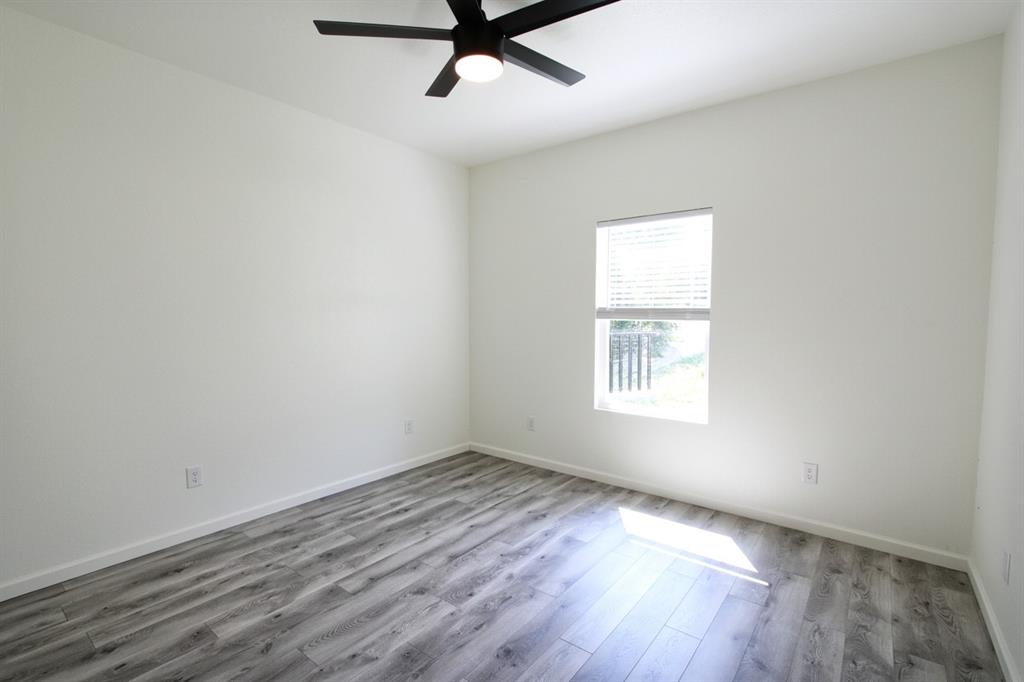842 White Oak Drive Woodway, TX 76712 - Photo 9 of 12 an empty room with wooden floor ceiling fan and windows