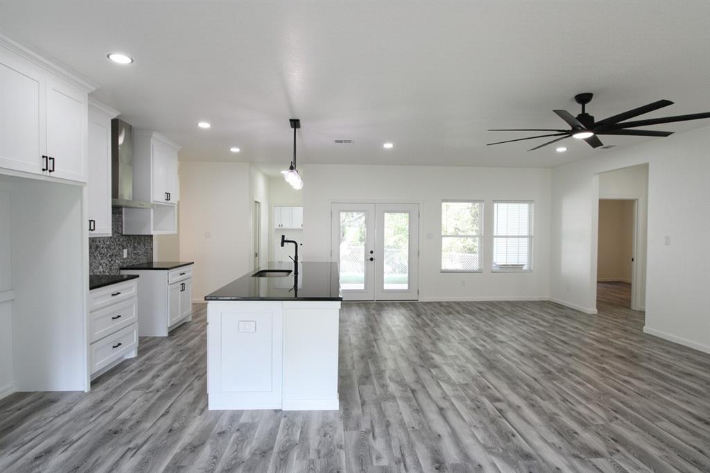 842 White Oak Drive Woodway, TX 76712 - Photo 2 of 12 a large kitchen with kitchen island a stove a sink a refrigerator and white cabinets with wooden floor