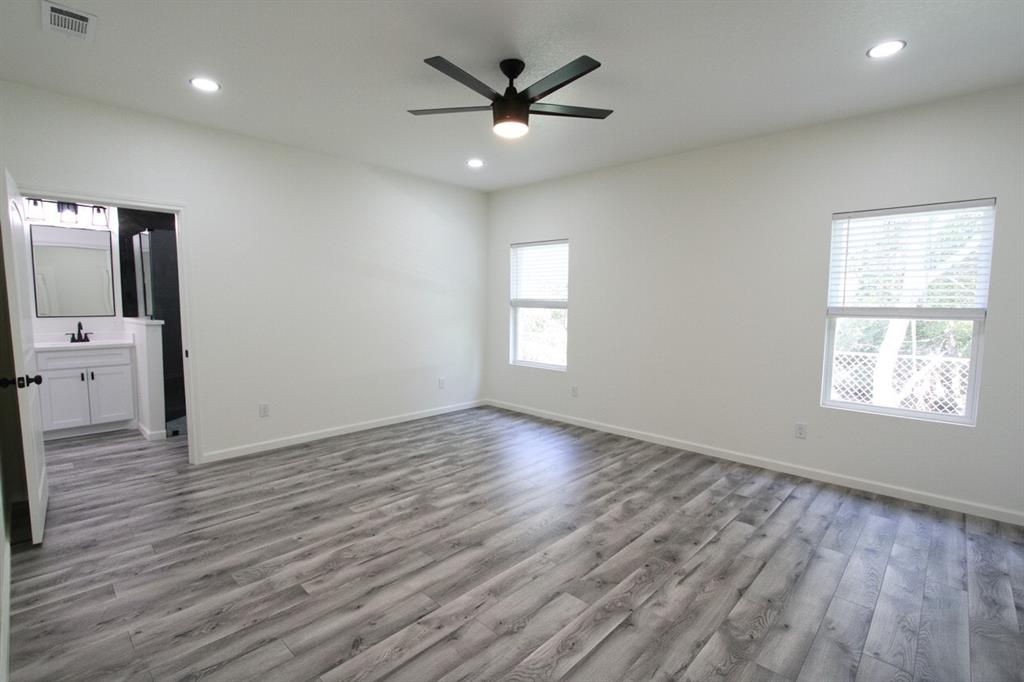 842 White Oak Drive Woodway, TX 76712 - Photo 4 of 12 an empty room with wooden floor chandelier fan and windows
