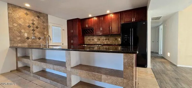 a kitchen with stainless steel appliances kitchen island granite countertop a refrigerator and cabinets