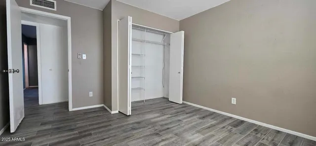 an empty room with wooden floor & closet area