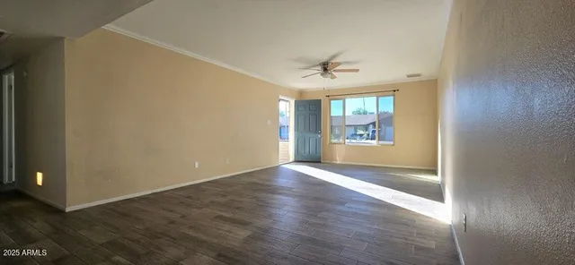 an empty room with wooden floor chandelier and windows