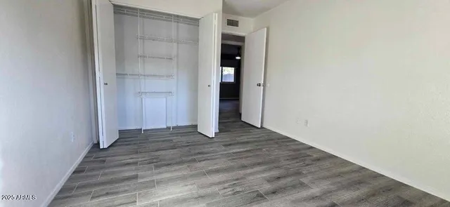 a view of an empty room with wooden floor and closet