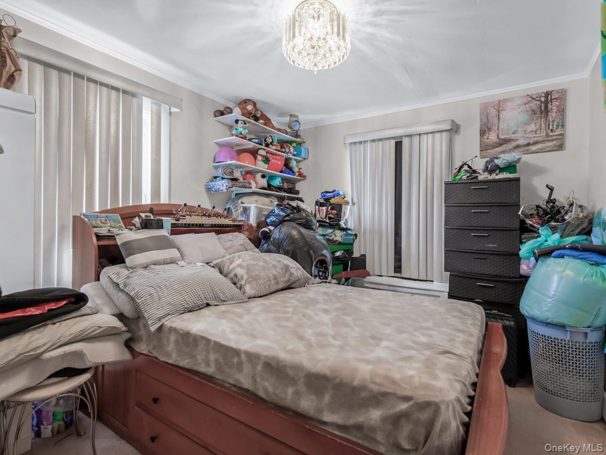 27-21 Coldspring Road Queens, NY 11691 - Photo 14 of 27 a bedroom with a bed and a chandelier