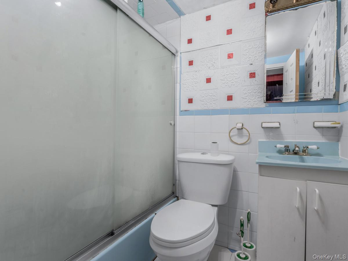 27-21 Coldspring Road Queens, NY 11691 - Photo 19 of 27 a white toilet sitting next to a white sink and cabinets