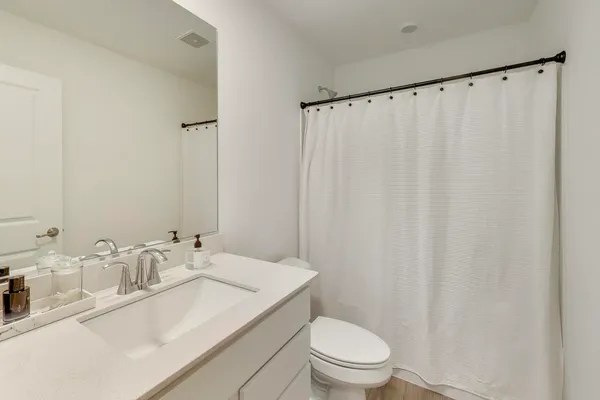 a bathroom with a granite countertop sink toilet and a mirror