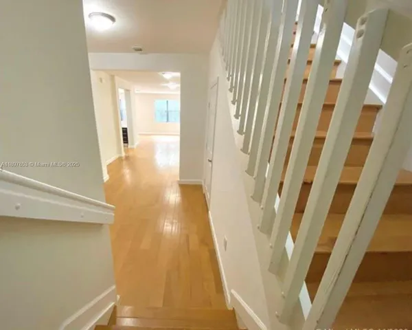 a view of a hallway with wooden floor and staircase