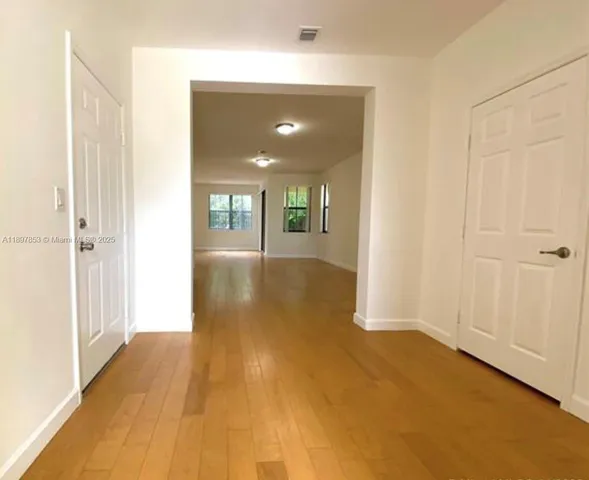 a view of a hallway with wooden floor and closet area