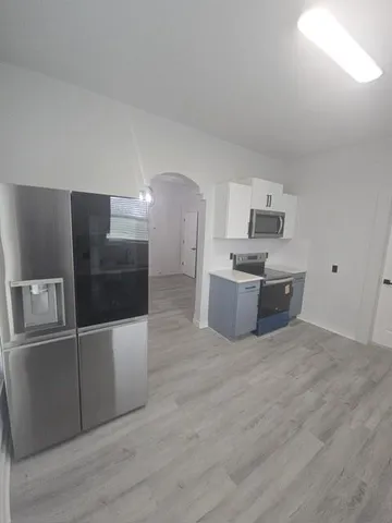 a large kitchen with stainless steel appliances a refrigerator and a sink