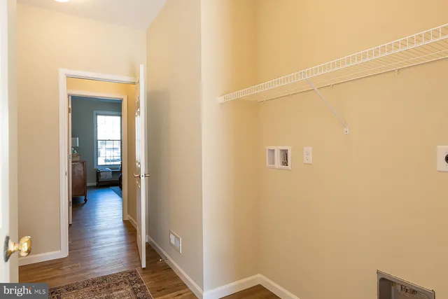 a view of a hallway with wooden floor and a bathroom