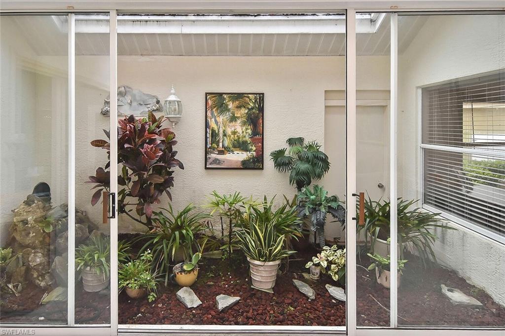 8928 Lely Island Circle Naples, FL 34113 - Photo 18 of 44 a potted plant sitting in front of a house