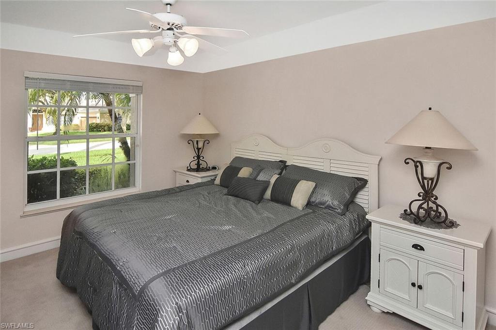 8928 Lely Island Circle Naples, FL 34113 - Photo 32 of 44 a bedroom with a large bed and a chandelier