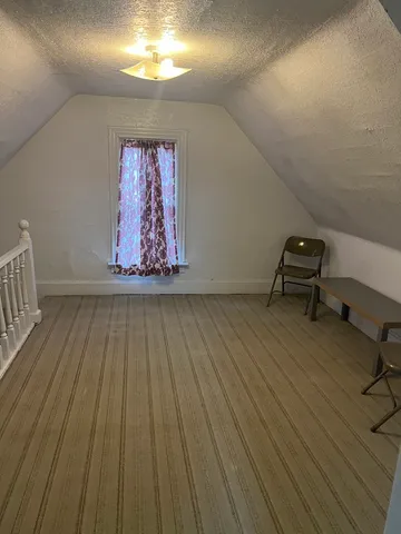 a view of a room with wooden floor a ceiling fan and furniture