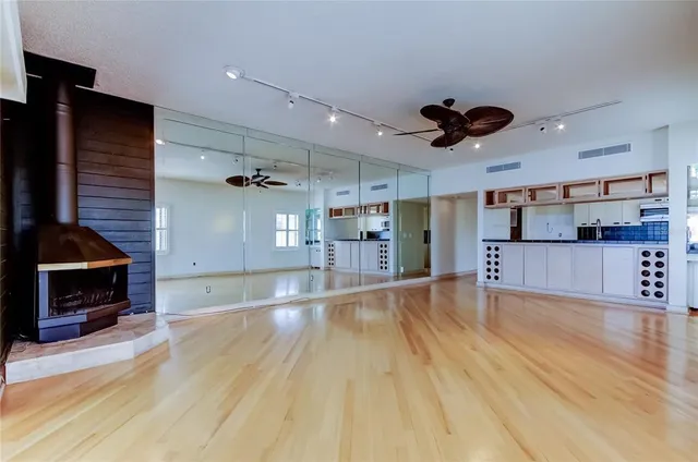 an empty room with wooden floor a kitchen view and a refrigerator