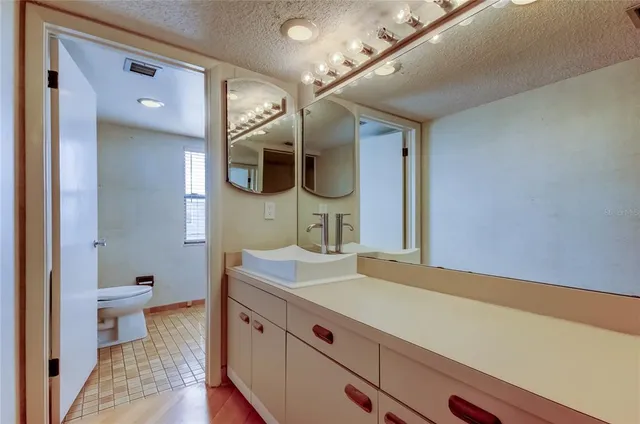 a spacious bathroom with a granite countertop sink a toilet and mirror