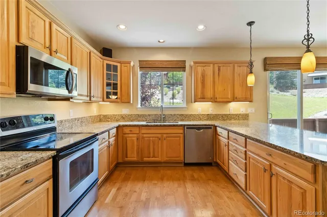 a kitchen with stainless steel appliances granite countertop wooden cabinets a stove top oven a sink and dishwasher next to a window