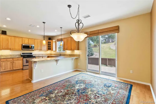 a kitchen with stainless steel appliances granite countertop a sink a stove a refrigerator cabinets and wooden floor