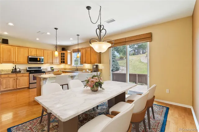 a kitchen with a dining table chairs and refrigerator