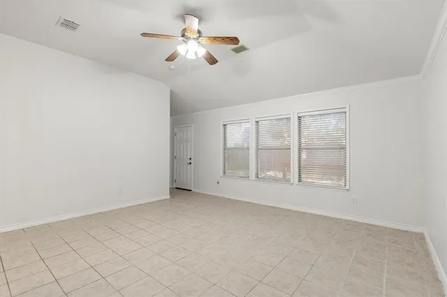 an empty room with chandelier fan and windows