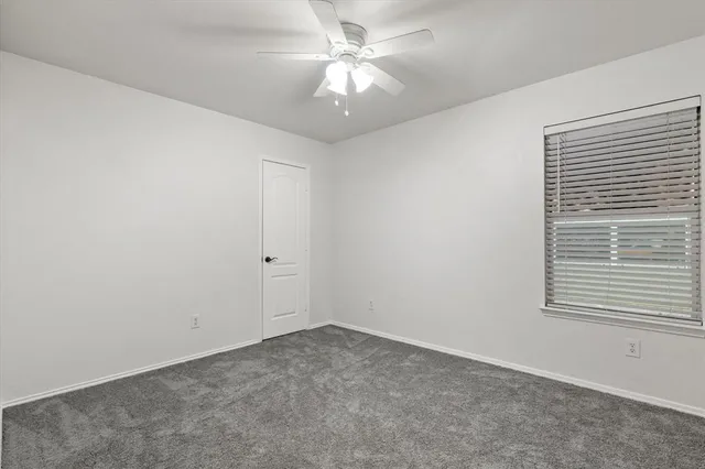 an empty room with a window and a fan
