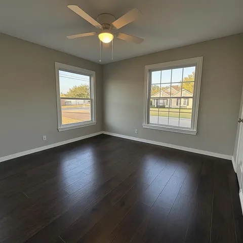 an empty room with wooden floor and windows