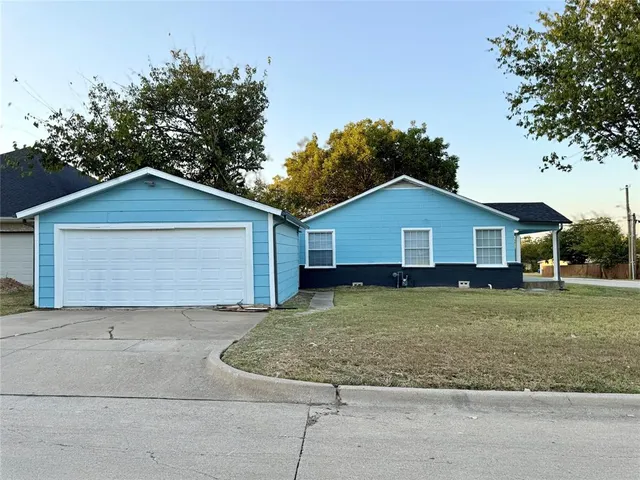 a view of a house with a yard plants and large tree