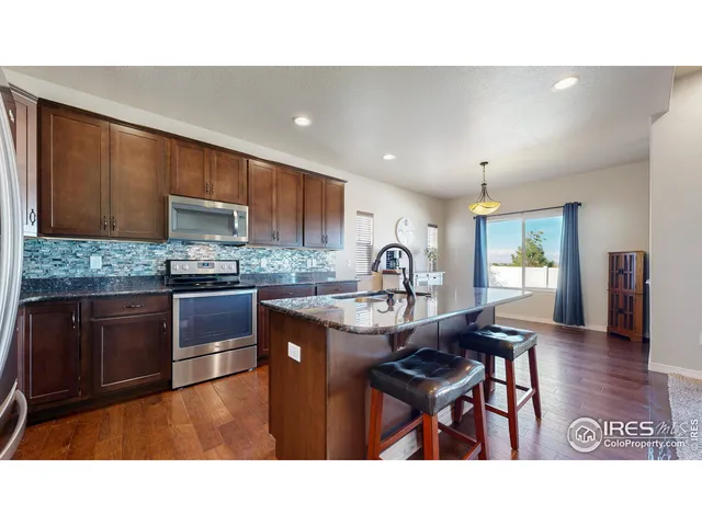 a kitchen with granite countertop a table chairs microwave and cabinets