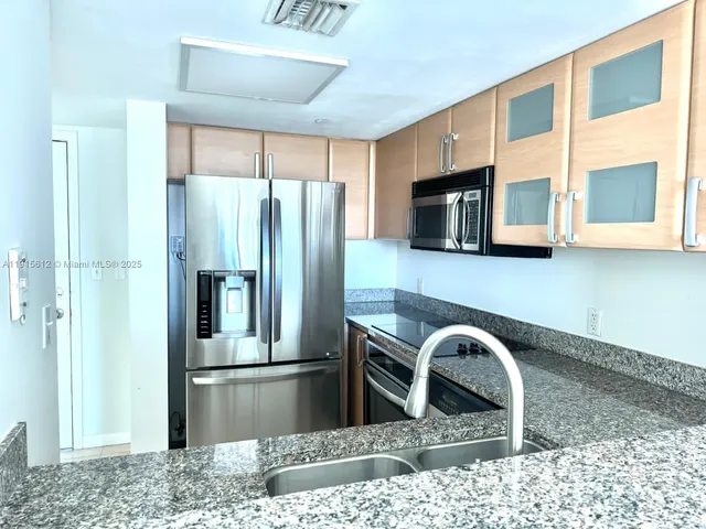 a kitchen with stainless steel appliances granite countertop a refrigerator a stove top oven a sink and dishwasher