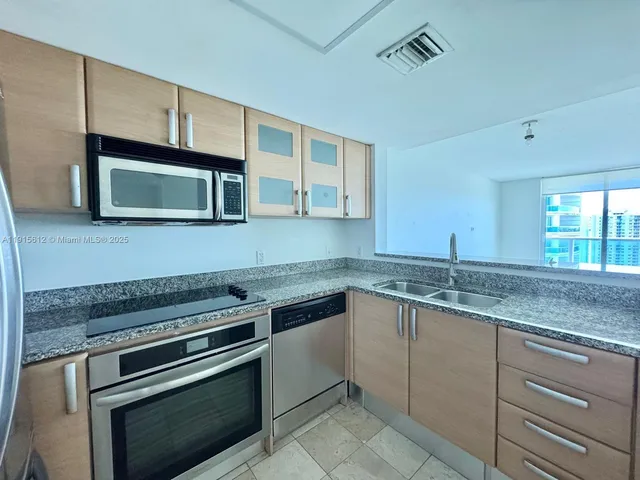 a kitchen with granite countertop cabinets stainless steel appliances and a sink