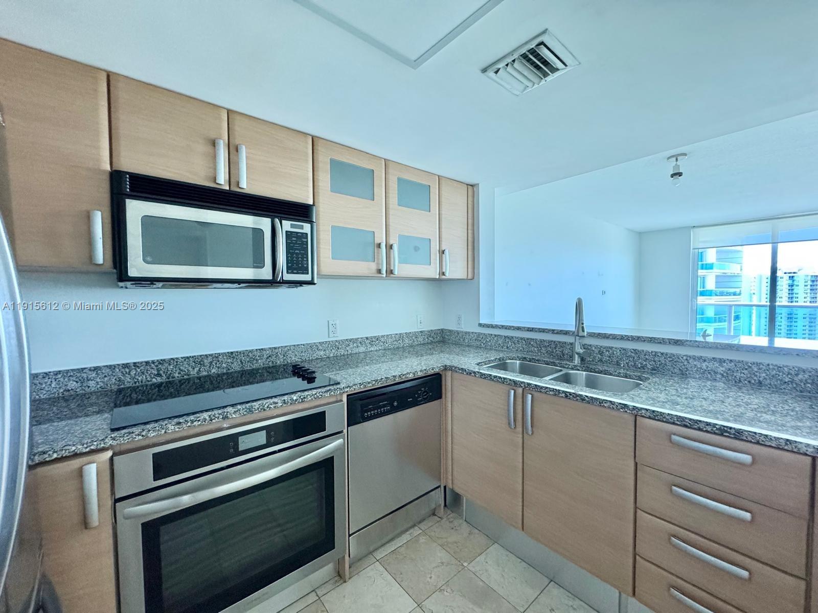 2101 Brickell Avenue, Unit 2411 Miami, FL 33129 - Photo 6 of 10 a kitchen with granite countertop cabinets stainless steel appliances and a sink