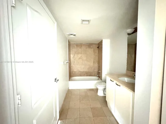 a bathroom with a granite countertop bathtub shower sink and toilet
