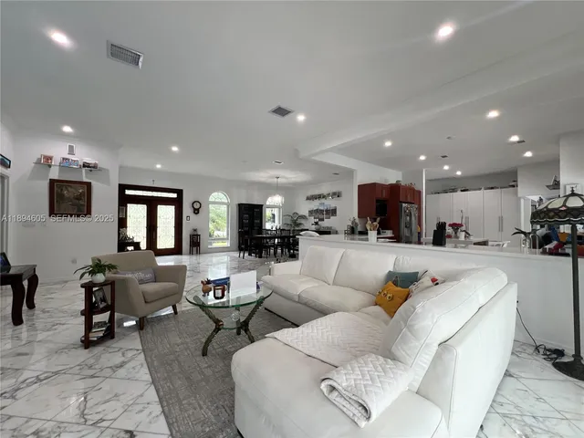 a living room with furniture kitchen view and a large window