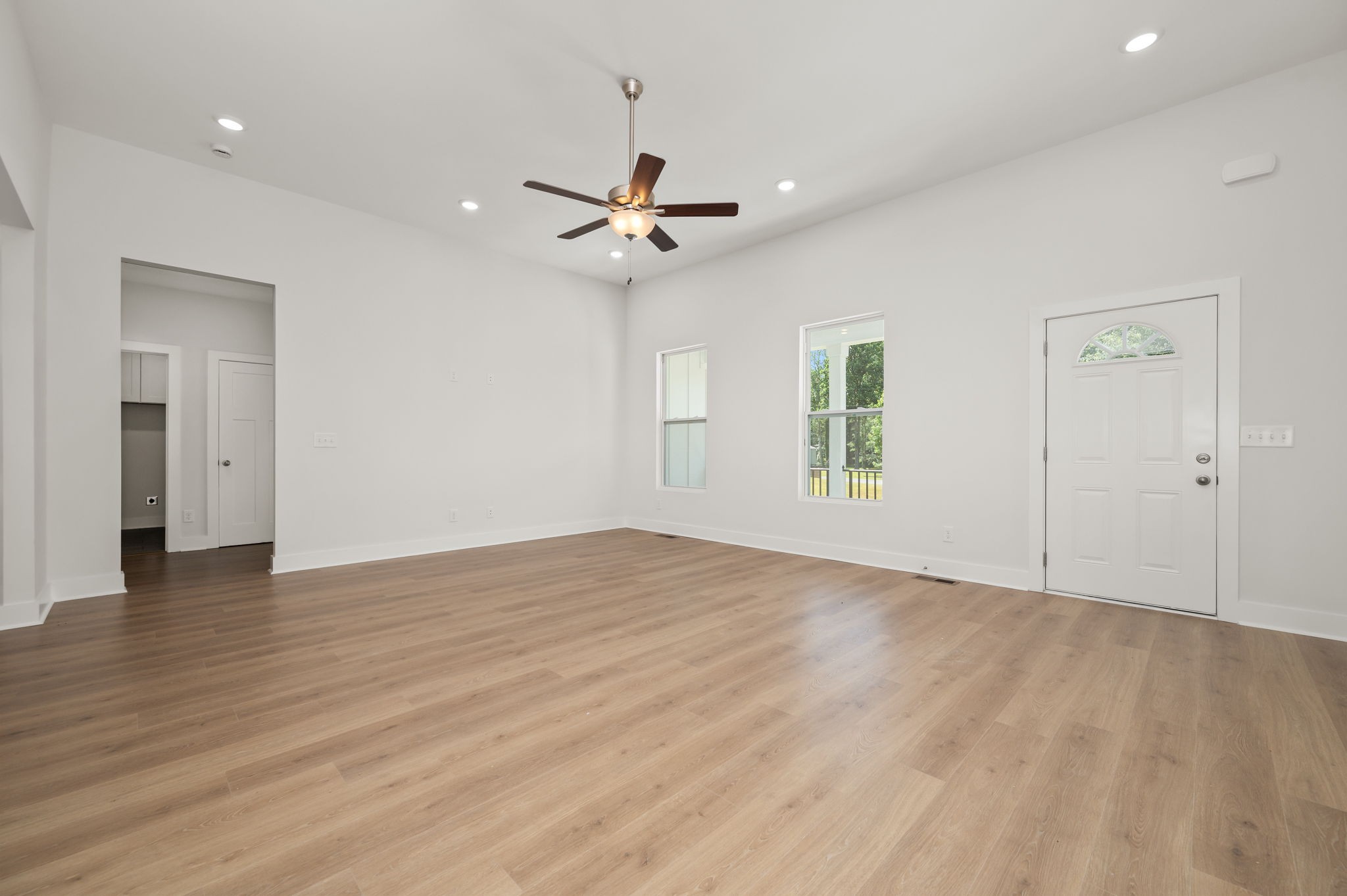 407 Spring Meadows Lane Morrison, TN 37357 - Photo 6 of 25 an empty room with wooden floor ceiling fan and windows