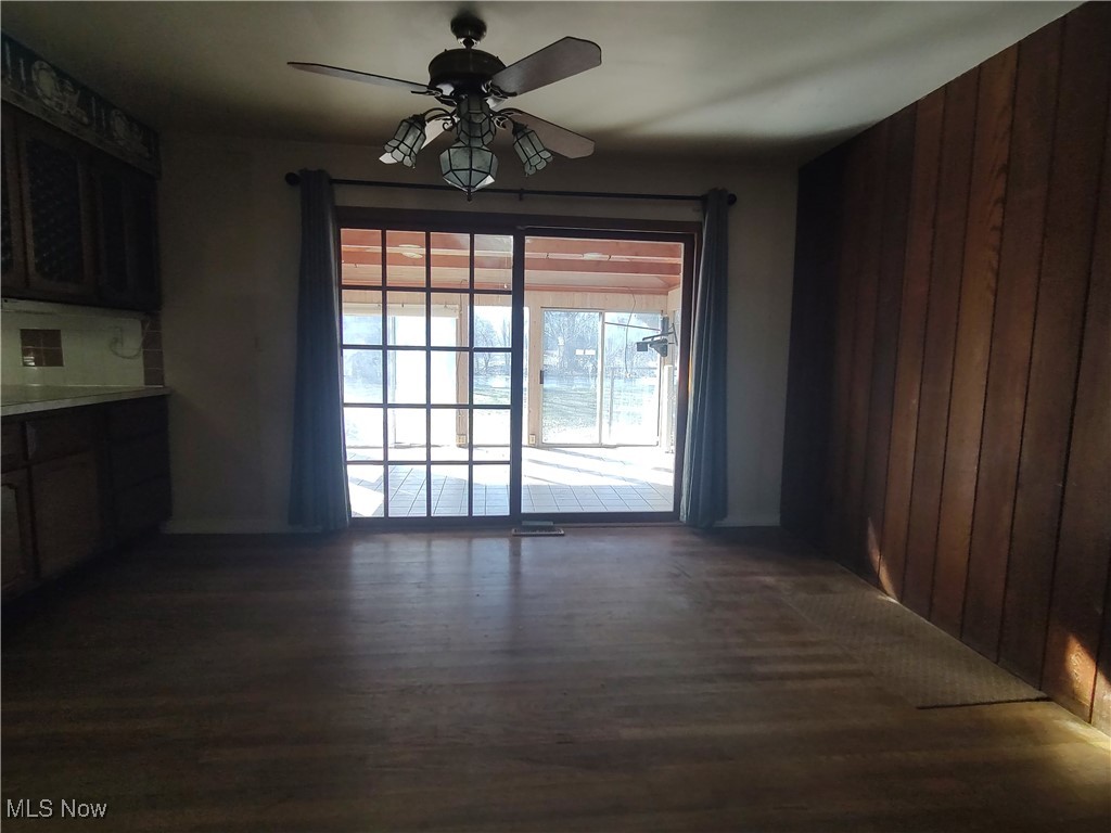 5704 Middle Ridge Road Madison, OH 44057 - Photo 16 of 50 Unfurnished dining area featuring ceiling fan, dark wood-style flooring, and wooden walls