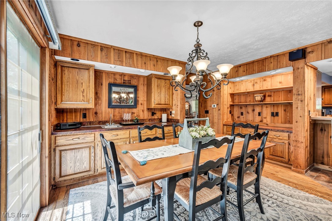 12938 Carter Road Painesville, OH 44077 - Photo 13 of 50 Dining area featuring wood walls, a chandelier, and light wood finished floors