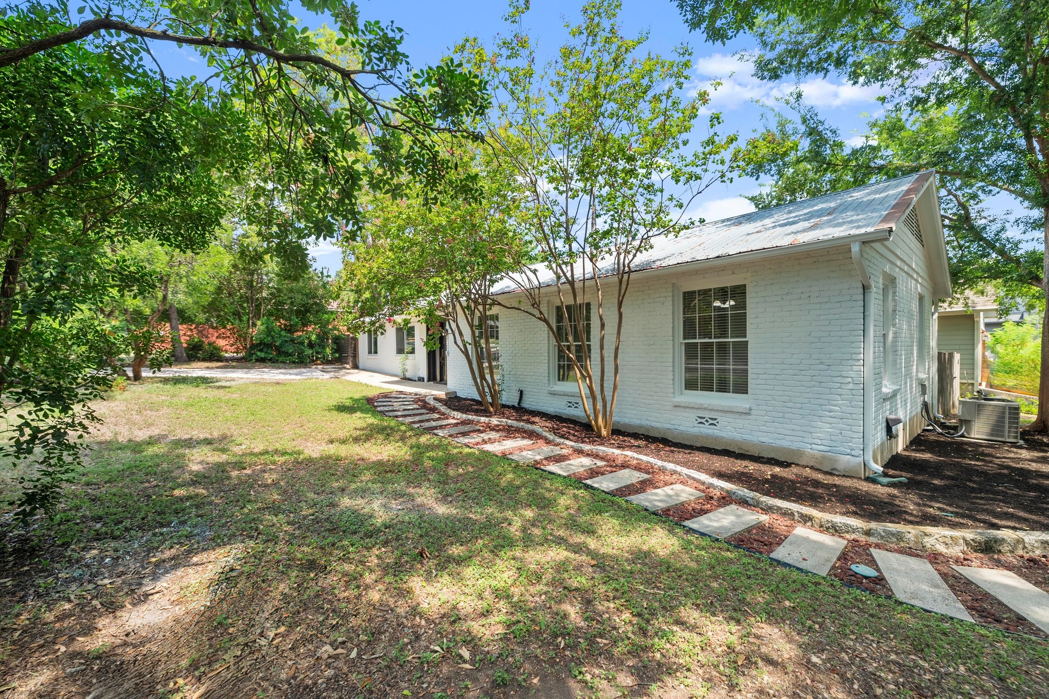 2640 West 45th Street Austin, TX 78731 - Photo 29 of 34 View of front facade featuring brick siding, a front yard, and a metal roof