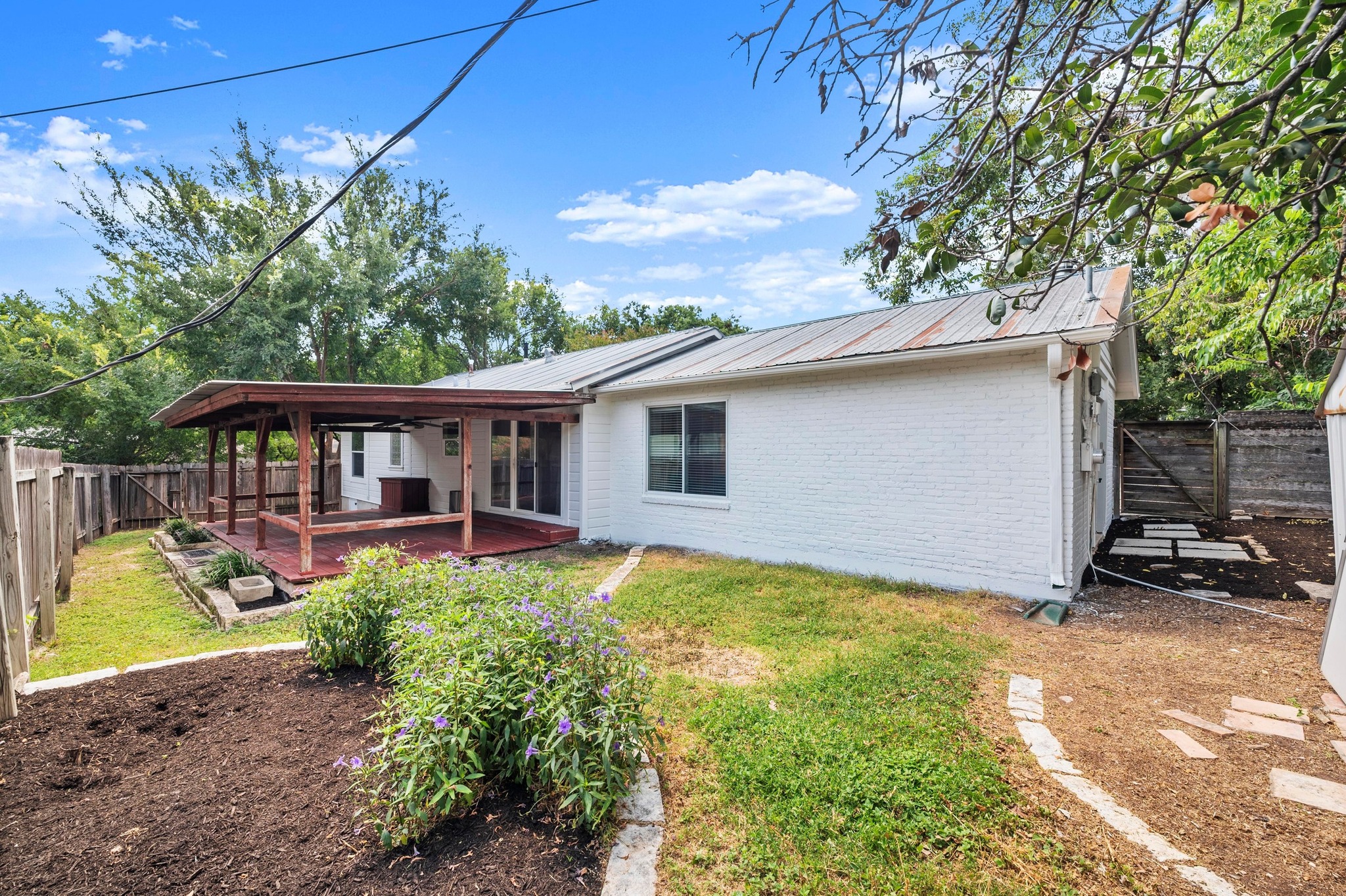 2640 West 45th Street Austin, TX 78731 - Photo 31 of 34 Back of property featuring a metal roof, brick siding, a fenced backyard, and a deck
