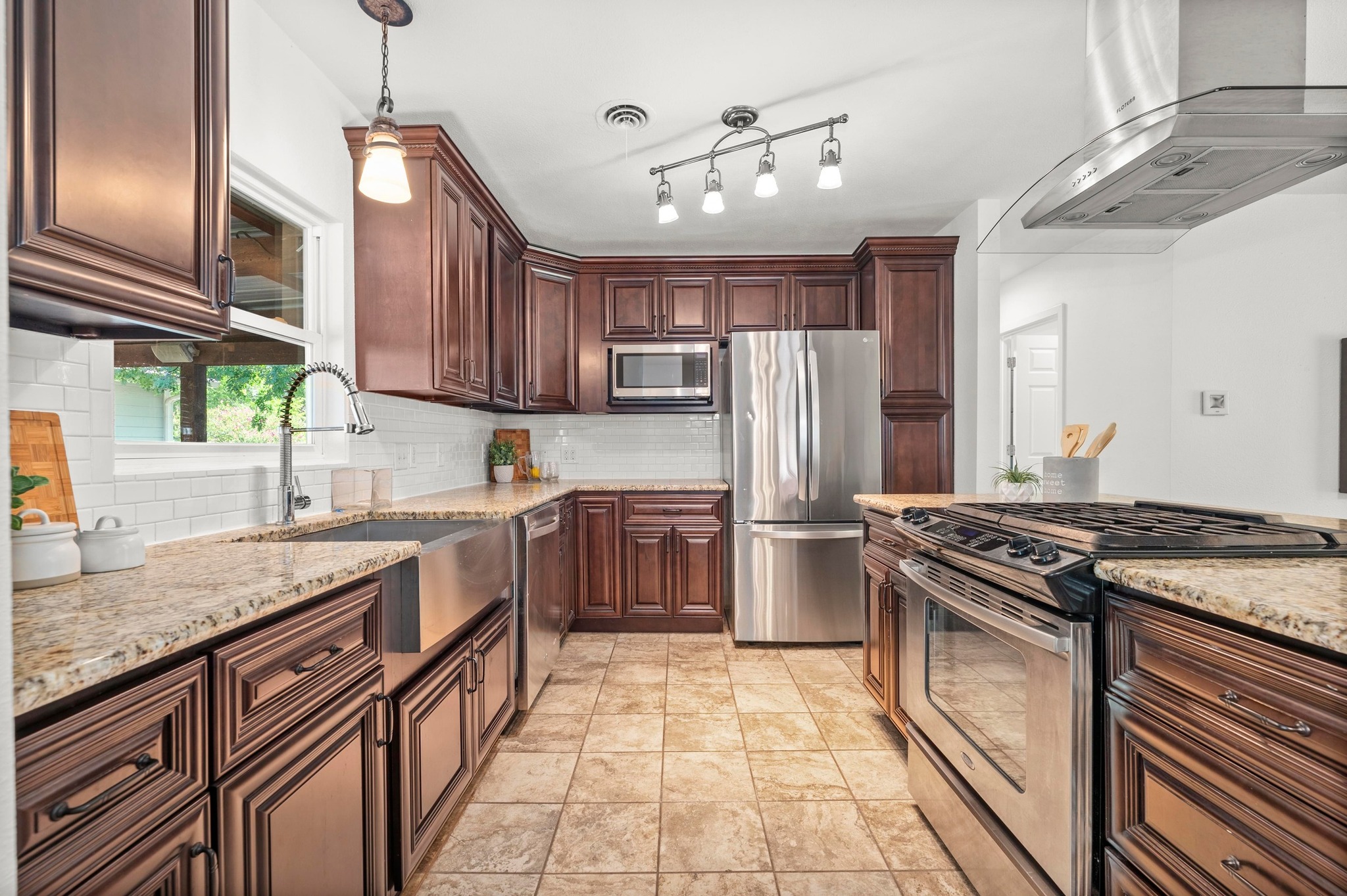2640 West 45th Street Austin, TX 78731 - Photo 10 of 34 Kitchen featuring appliances with stainless steel finishes, exhaust hood, light stone counters, and tasteful backsplash