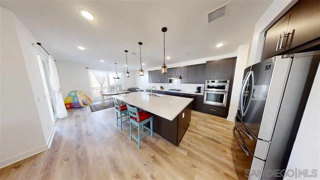 9048 West Bluff Place Santee, CA 92071 - Photo 5 of 14 a kitchen with stainless steel appliances granite countertop a refrigerator a sink dishwasher a stove and white countertops with wooden floor