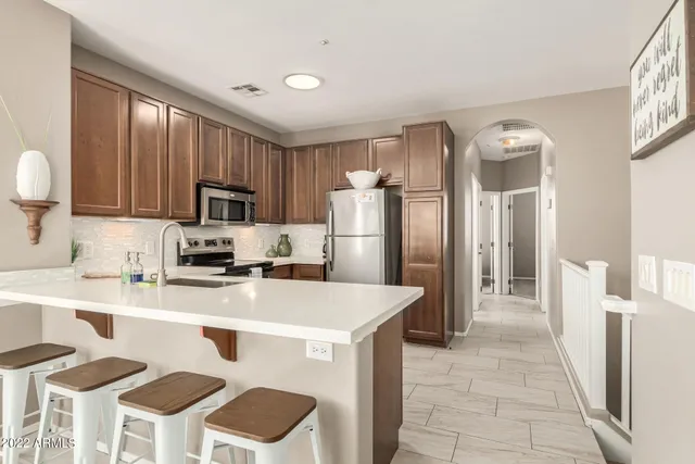 a kitchen with stainless steel appliances granite countertop a refrigerator a stove a sink dishwasher and white cabinets with wooden floor