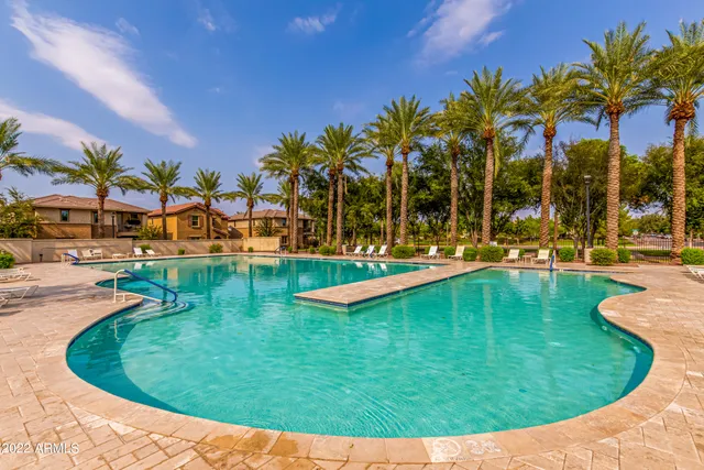 a view of a swimming pool with a lawn chairs under palm trees