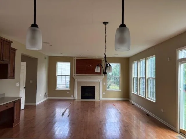 a view of an empty room with wooden floor fireplace and a window