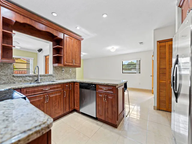 a large kitchen with stainless steel appliances granite countertop a sink and a refrigerator