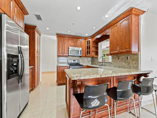 a kitchen with stainless steel appliances granite countertop a refrigerator and a stove top oven