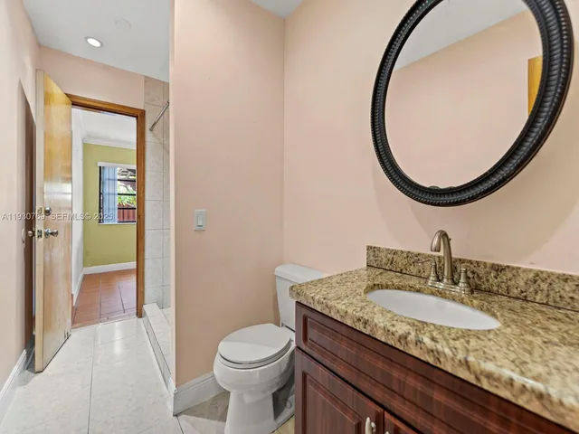 a bathroom with a granite countertop sink a toilet and a mirror